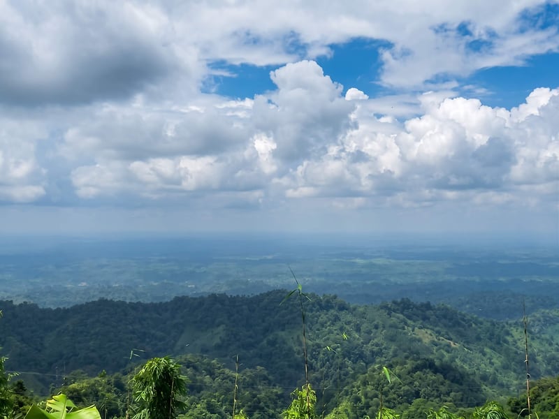 Layered forested hills fading into haze under a tall cloudy sky